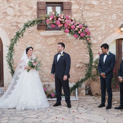 bride & groom at ceremony arch at rustic villa wedding in Crete