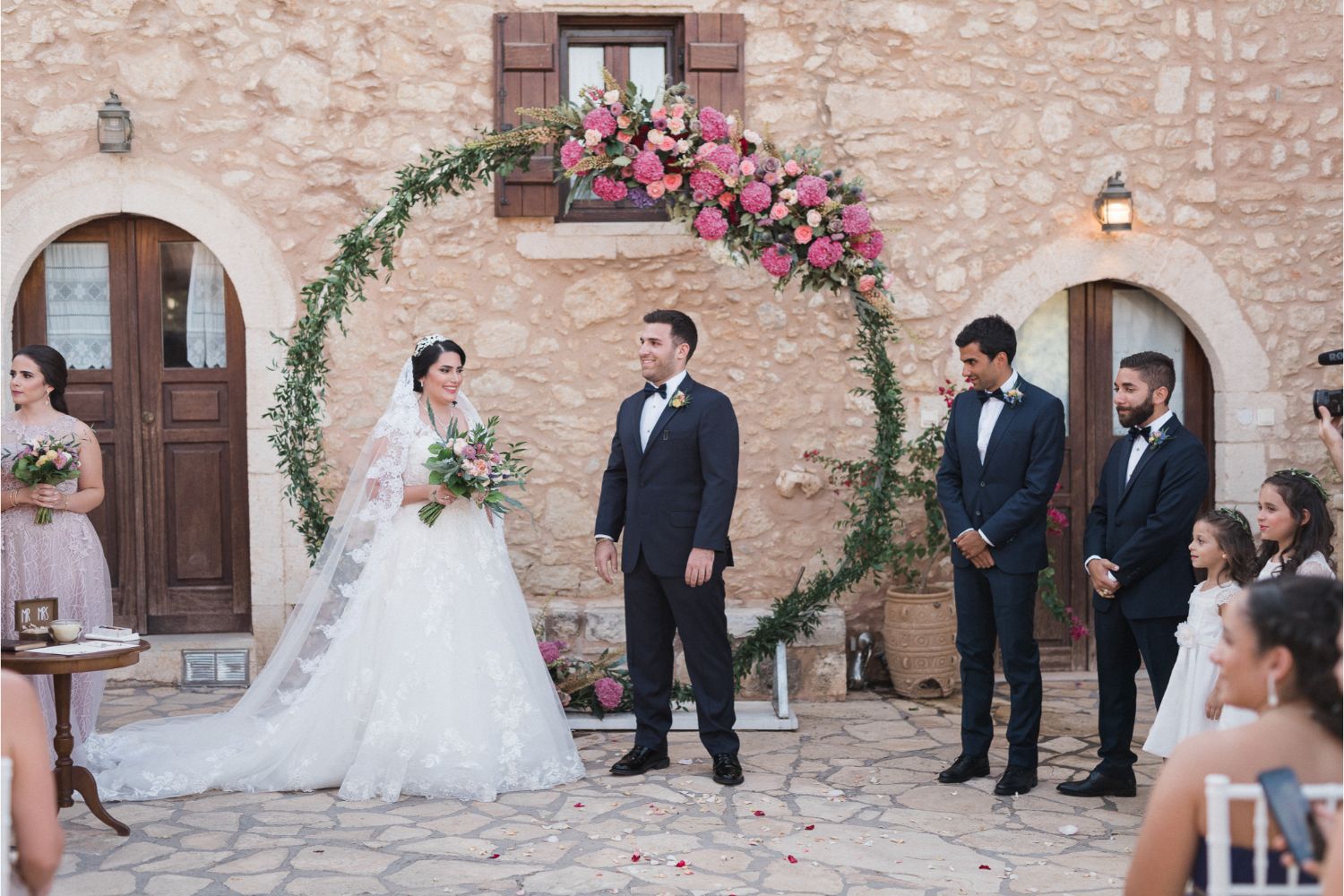 bride & groom at ceremony arch at rustic villa wedding in Crete